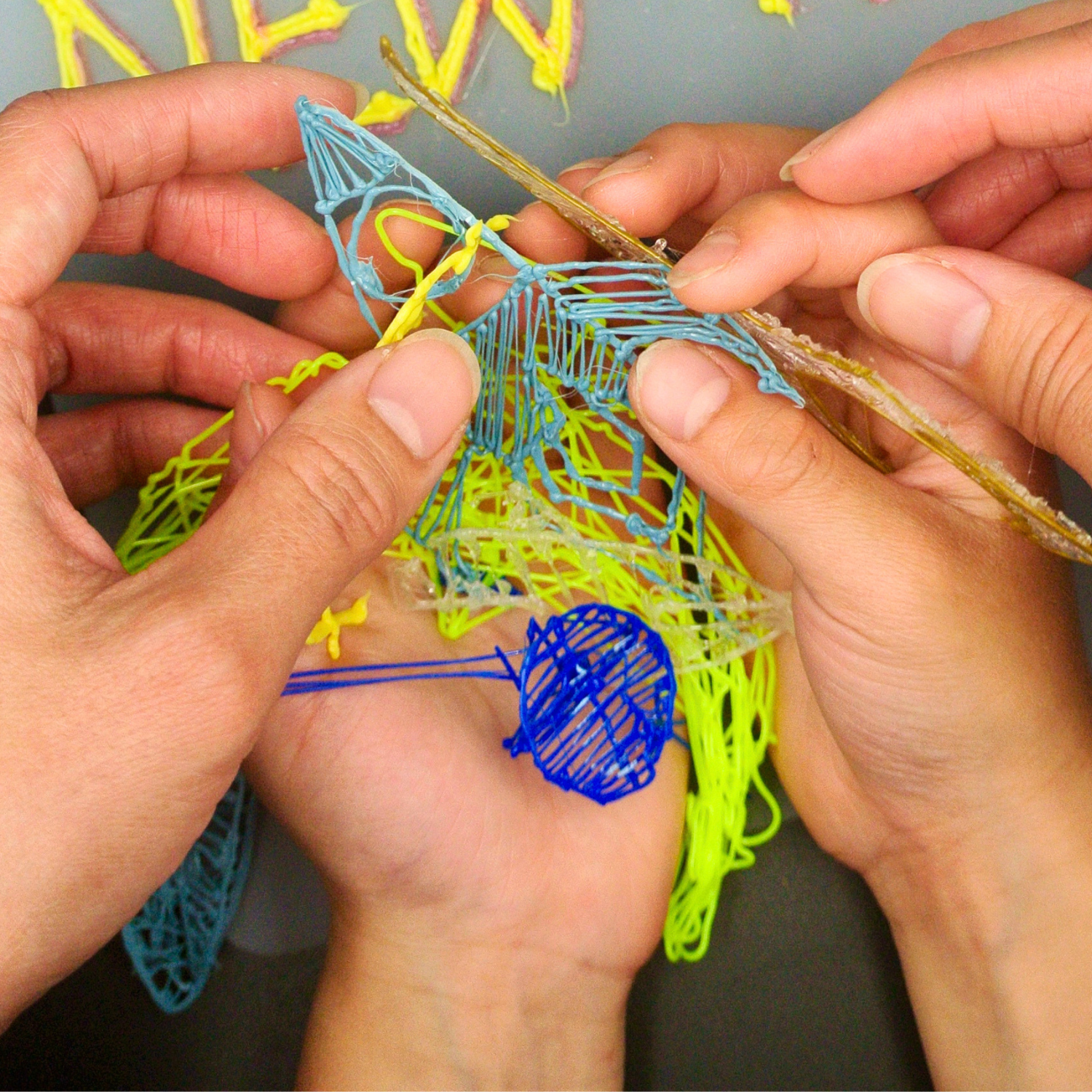 Two pairs of hands holding completed 3D pen creations