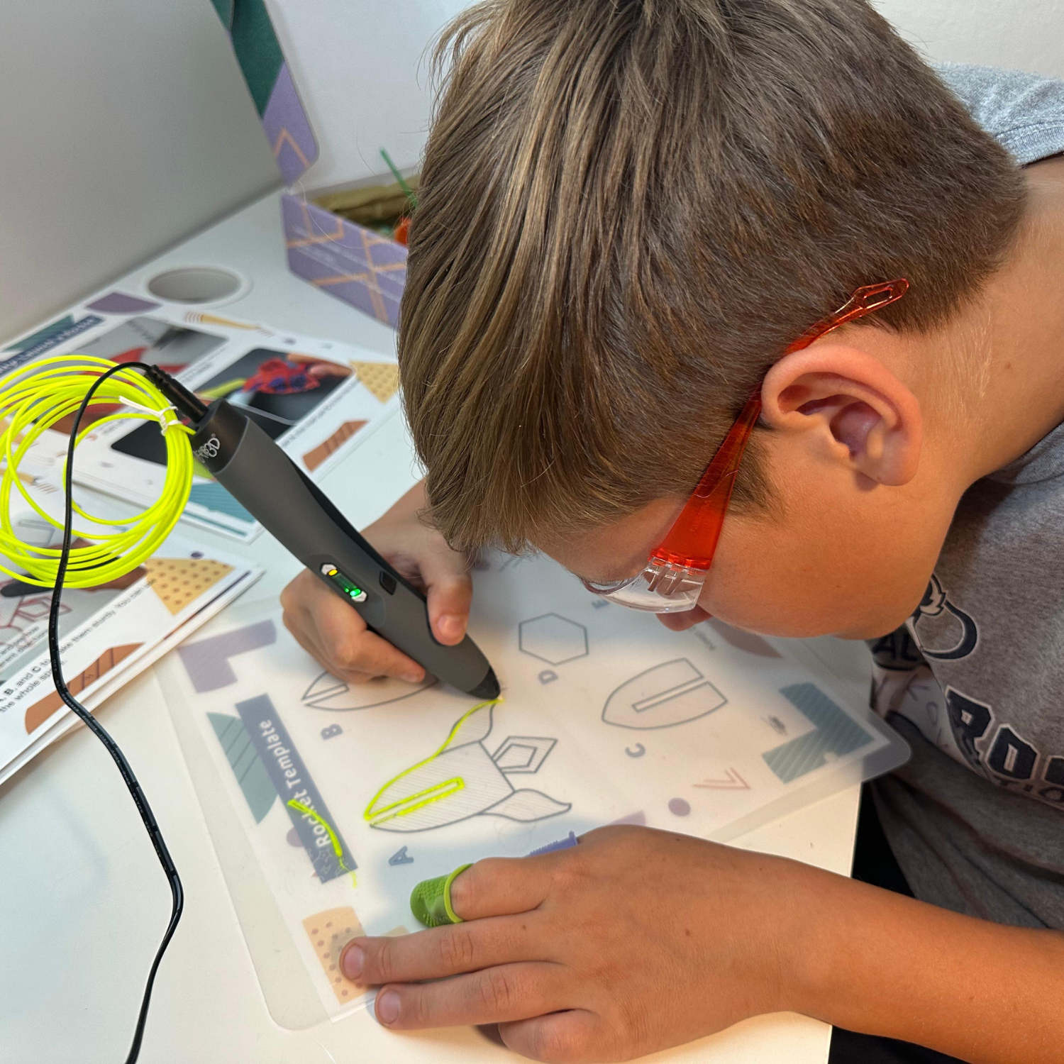 Child using 3D pen with safety goggles and curriculum guide